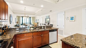 A spacious kitchen with granite countertops, wooden cabinets, and a built-in dishwasher.