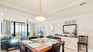 A spacious living room with a dining area, large windows, and a view of the outdoors.