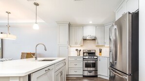 Una cocina moderna con armarios blancos, electrodomésticos de acero inoxidable y piso de madera.