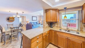 A kitchen with wooden cabinets, a granite countertop, and a window with a view. - Savor Gulf Views! 3/3 Heated Pool/Spa, Beachside - 603 (Redington Shores)