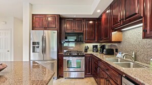 Una cocina moderna con encimeras de granito, electrodomésticos de acero inoxidable y armarios de madera.
