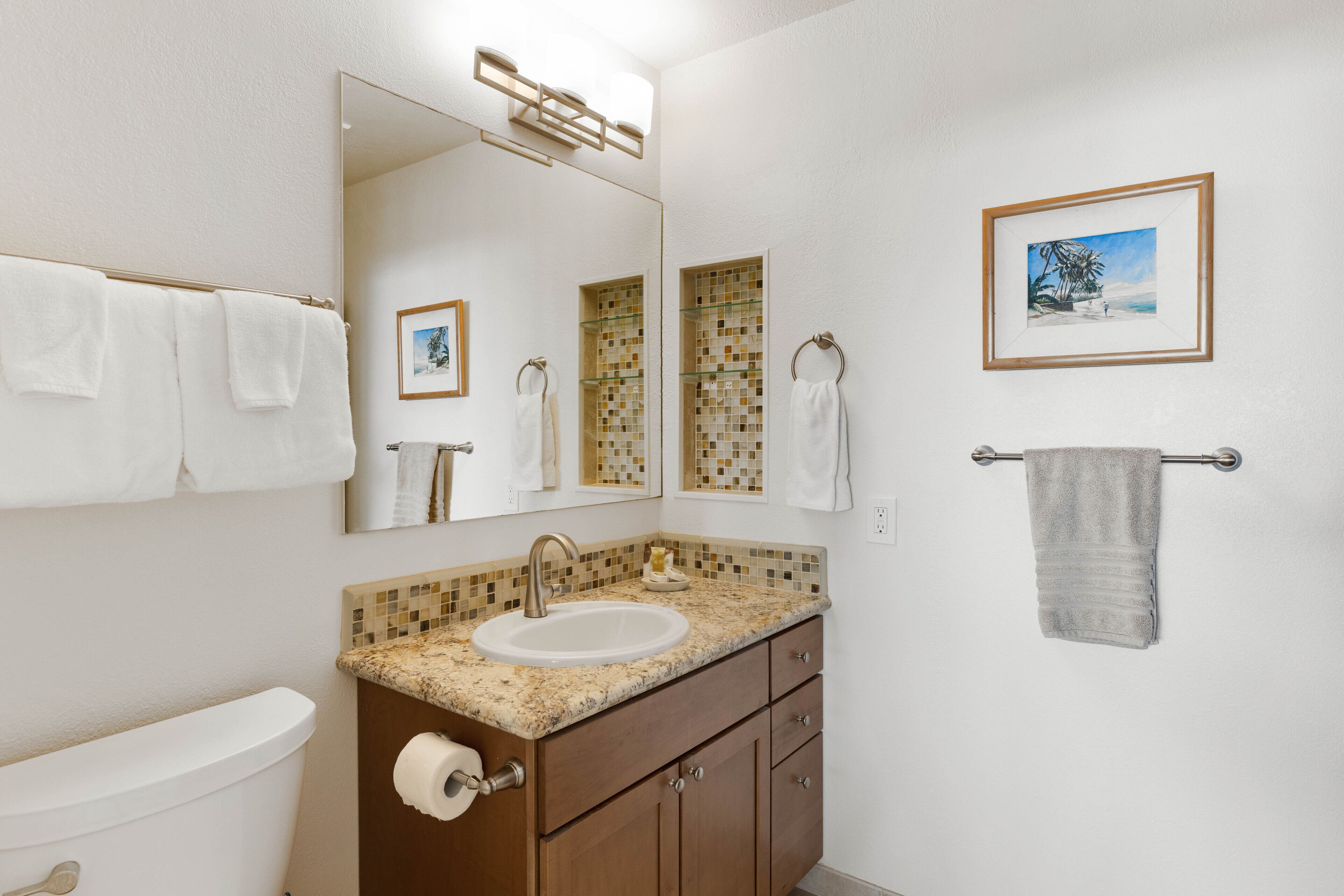 A bathroom with a toilet, sink, vanity, and towel rack.