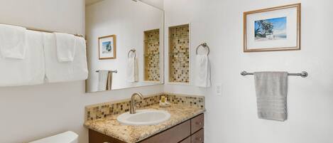 A bathroom with a toilet, sink, vanity, and towel rack.