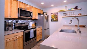 Una cucina moderna con mobili in legno, elettrodomestici in acciaio inossidabile e una grande isola con lavello.