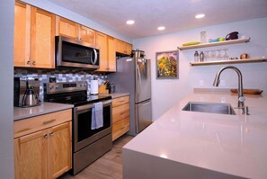 Une cuisine moderne avec des meubles en bois, des appareils en acier inoxydable et un grand îlot central doté d’un évier.