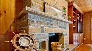 A stone fireplace with a wooden mantel, a ship's wheel, and a wooden bucket. - Van Horne Villa | Beautiful Home, Ocean Views! (Tybee Island)