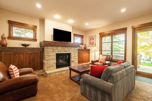 A living room with a stone fireplace, leather furniture, a flat-screen TV, and large windows. - Unbeatable Location, Hot Tub, Luxury Townhome Park City Silver Star Ultimate! Ski In- Out! (Park City)
