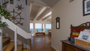 Une pièce spacieuse avec un escalier en bois, une vue sur la mer et un meuble en bois contenant des documents.