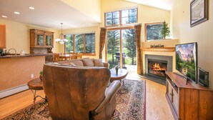 A spacious living room with a fireplace, large windows, and a cozy seating area. - Highland Greens Fairway Townhome: Hot Tub, Views (Breckenridge)