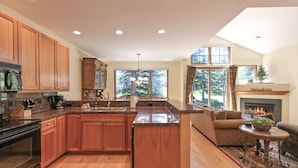 A spacious kitchen with wooden cabinets, a central island, and a fireplace. - Highland Greens Fairway Townhome: Hot Tub, Views (Breckenridge)