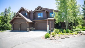A two-story house with a garage, a driveway, and a landscaped garden. - Highland Greens Fairway Townhome: Hot Tub, Views (Breckenridge)
