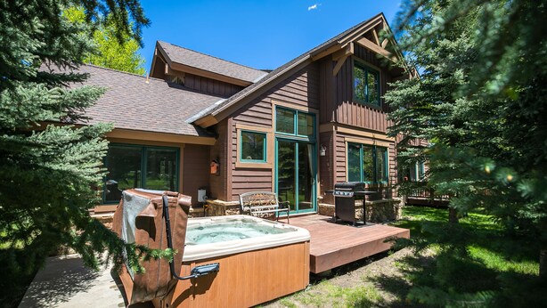 A wooden cabin with a hot tub, deck, and large windows. - Highland Greens Fairway Townhome: Hot Tub, Views (Breckenridge)