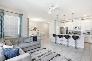 Uma sala de estar moderna com um sofá, uma mesa de centro e uma área de refeições com cadeiras.