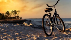 Una bicicleta estacionada en una playa arenosa, con un atardecer de fondo.