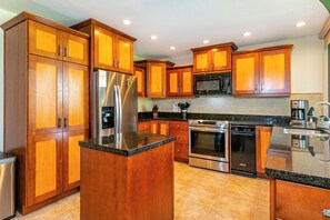 A modern kitchen with wooden cabinets, stainless steel appliances, and a granite countertop.