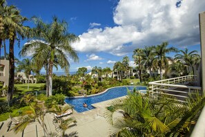 Een resort met een zwembad, omringd door palmbomen en uitzicht op de oceaan.