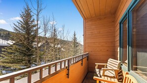 A wooden balcony with two wooden chairs, a view of trees and a snowy landscape. - Short Walk to Lifts, Shops, and Dining! Private Balcony with Slope Views (Keystone)