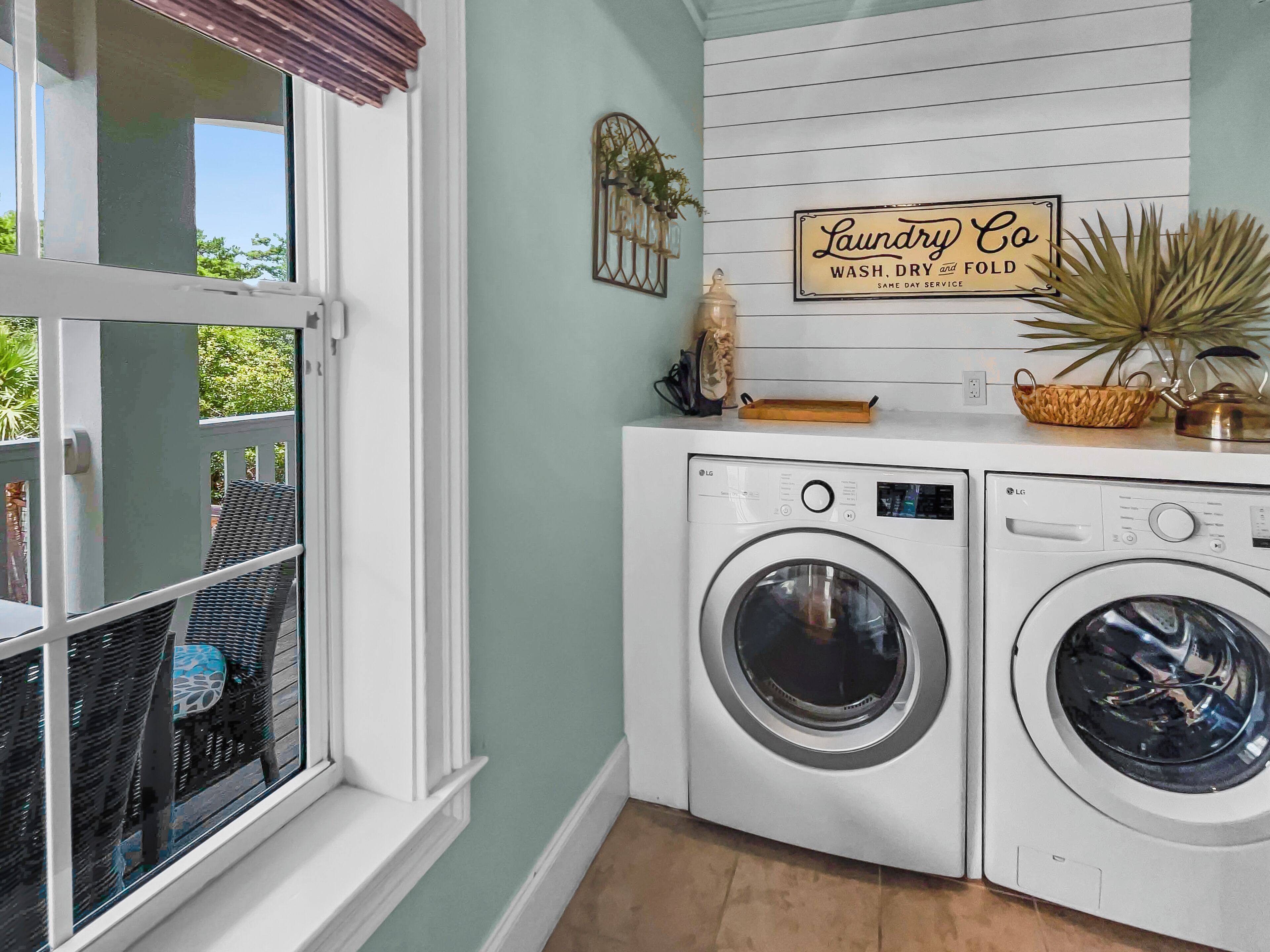 Een wasserette met twee witte LG wasmachines, een raam met uitzicht op groen, en een 'Laundry Co' bord aan de muur.