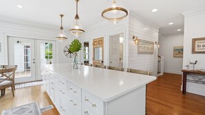 A spacious kitchen with white cabinetry, a large island, and pendant lighting.