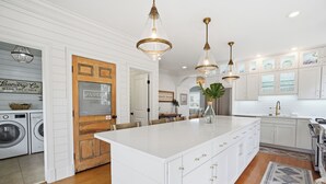 A spacious kitchen with white cabinetry, a large island, and pendant lighting.