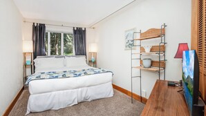 Une chambre d’hôtel équipée d’un lit, d’un bureau, d’une télévision et d’une étagère avec des paniers.