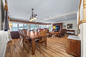 Un vaste espace dédié à la salle à manger, avec une table et des chaises en bois, une cheminée et une vue sur l’extérieur.