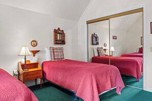 A hotel room with two beds, a wooden nightstand, a mirror, and a wall-mounted shelf.