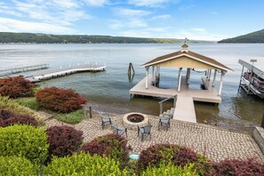 Un belvédère doté d’un foyer et de sièges extérieurs, situé au bord d’un lac et entouré de jardins aménagés.