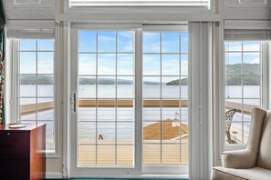 A room with a large sliding glass door leading to a deck overlooking a body of water.