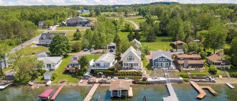 A lakeside property with docked boats, a marina, and houses with large windows and porches.