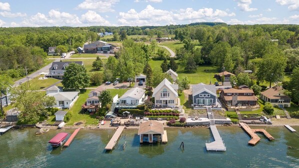 A lakeside property with docked boats, a marina, and houses with large windows and porches.