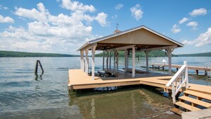 Eine Holzsteg mit überdachter Sitzgruppe und einem kleinen Pavillon an einem See.