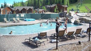Ett poolområde med solstolar, en fontän och en bergig bakgrund.