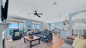 A spacious living area with a sofa, armchairs, a coffee table, and a dining area with a kitchen in the background.