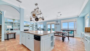 A spacious kitchen with a large island, white cabinetry, and a view to the outside.