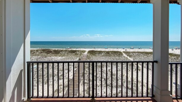 A balcony with a view of the beach and ocean.