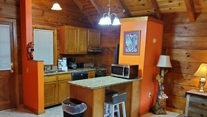 Una cocina acogedora con armarios de madera, un microondas y una pequeña isla con taburetes.