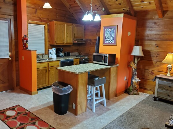A cozy kitchen with wooden cabinets, a microwave, and a small island with stools.