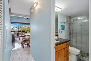 Ein Badezimmer mit einer Duschkabine aus Glas, einer weißen Toilette und Holzschränken.