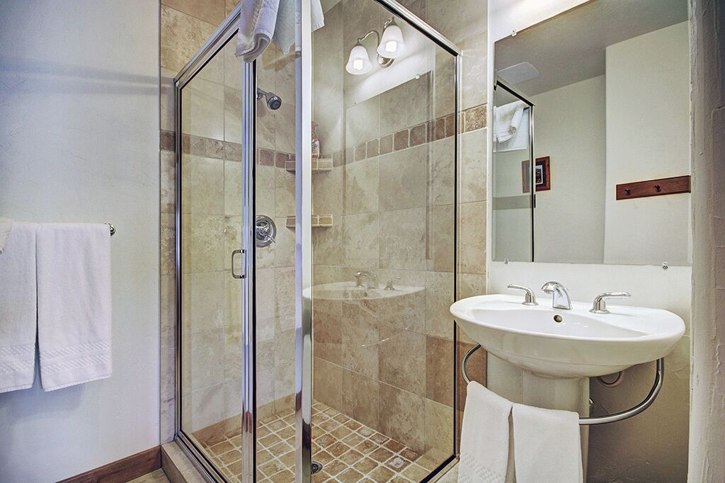 A modern bathroom with a glass-enclosed shower, a large sink, and a mirror.