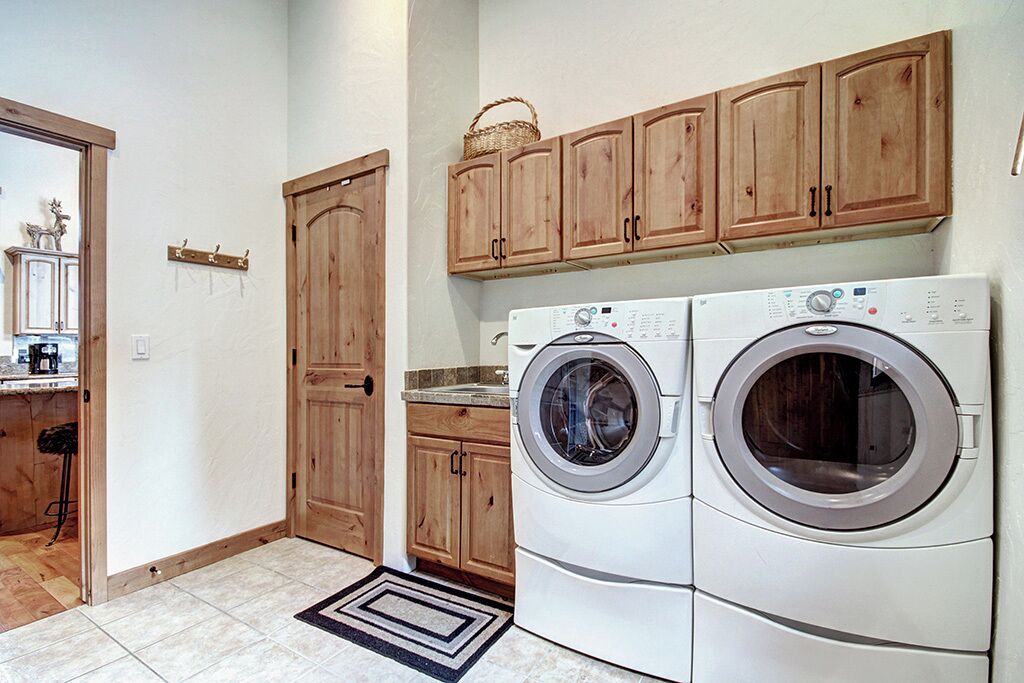 A laundry room with wooden cabinets, a washing machine, and a dryer.