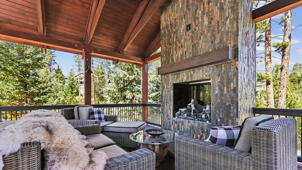 A covered outdoor seating area with wicker furniture and a stone wall.