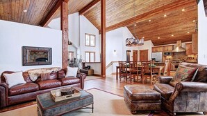 A spacious living room with a fireplace, leather sofas, and a dining area with wooden furniture.