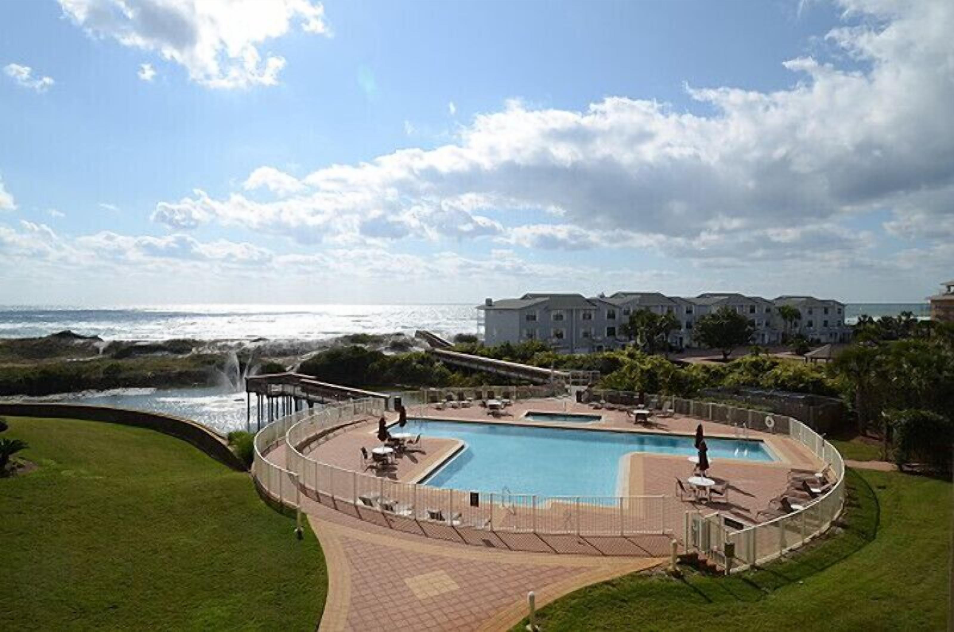 A resort with a large pool, a beach view, and a building with multiple balconies.