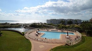 Un resort con una piscina grande, vista a la playa y un edificio con varios balcones.