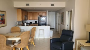 Una sala de estar moderna con comedor, cocina y un sillón de cuero negro.