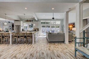 A spacious kitchen with a central island, wooden flooring, and a view to the outdoors.