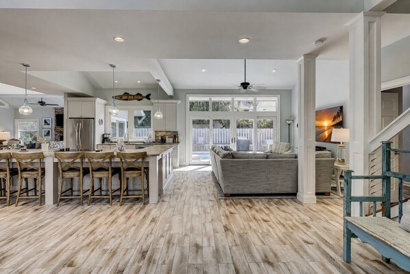 A spacious kitchen with a central island, wooden flooring, and a view to the outdoors.