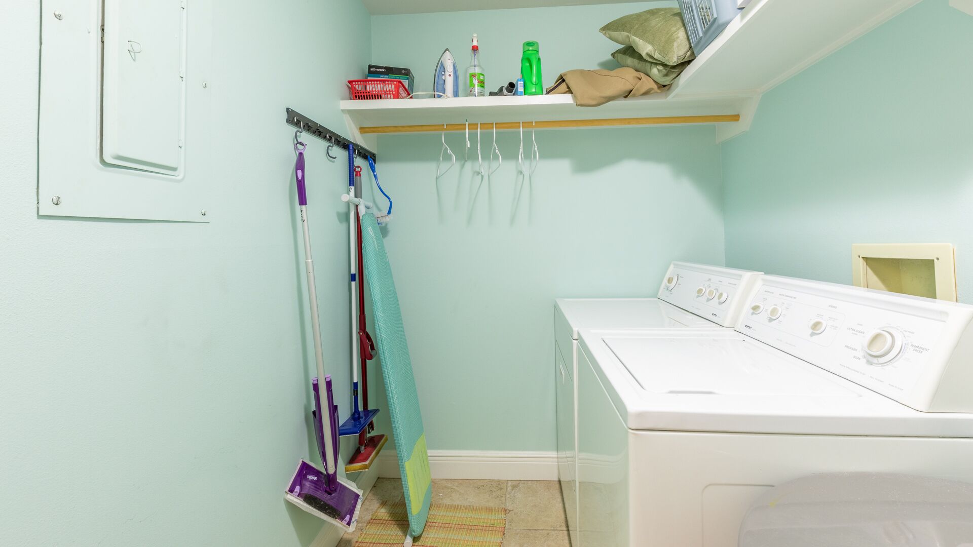 A laundry room with a washing machine, a drying rack, and a shelf with cleaning supplies.