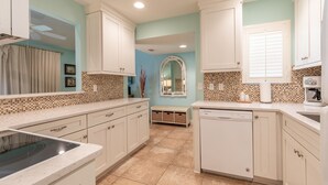 A kitchen with white cabinets, a dishwasher, a coffee maker, and a tiled backsplash. - Charming 2BR Beach Villa! GOLF CART, Tram, Beach, Pool, Porch, Near Baytowne. (Destin)